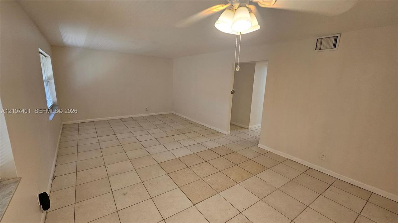 Interior space featuring light-toned ceramic tile flooring, neutral wall paint, and a ceiling-mounted light fixture with three glass shades