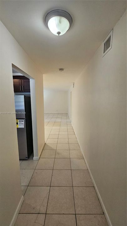 Neutral-toned ceramic tile flooring throughout, featuring a flush-mount ceiling light fixture