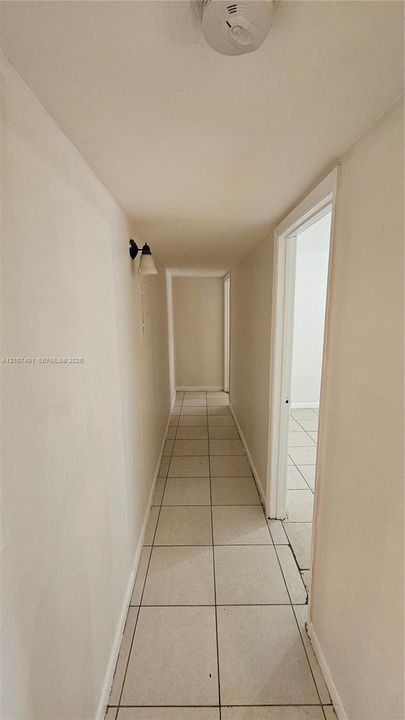 Hallway featuring ceramic tile flooring, neutral wall finishes, and a wall-mounted light fixture