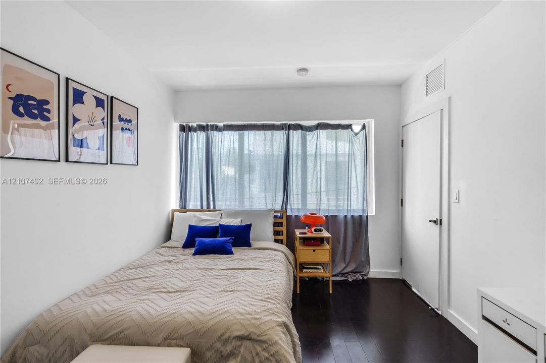 Dark wood-finish flooring, smooth white wall finishes, and a wide window with natural light exposure