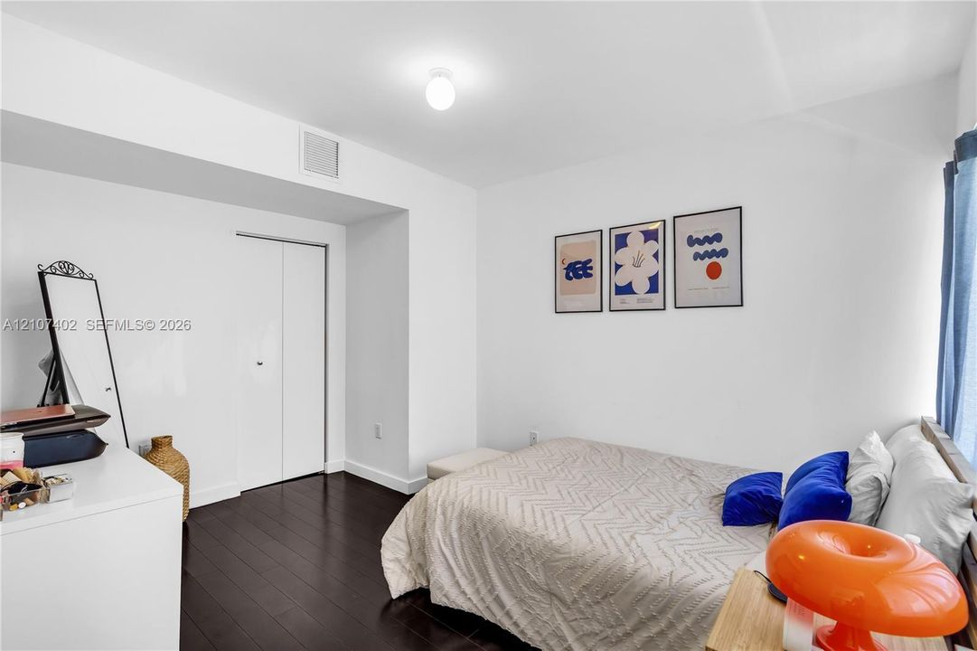 Room featuring dark wood-finish flooring, white walls, and a recessed closet with bi-fold doors