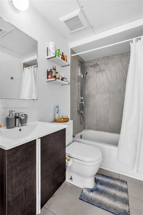 Dark wood-finish vanity with a white integrated sink, wall-mounted shelving, shower panel system with a rainfall showerhead, and textured stone-finish shower surround
