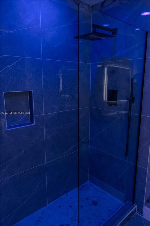 Stone-patterned wall surfacing, floating vanity with integrated rectangular sink, wall-mounted faucet, illuminated mirror, and large-format floor tiling