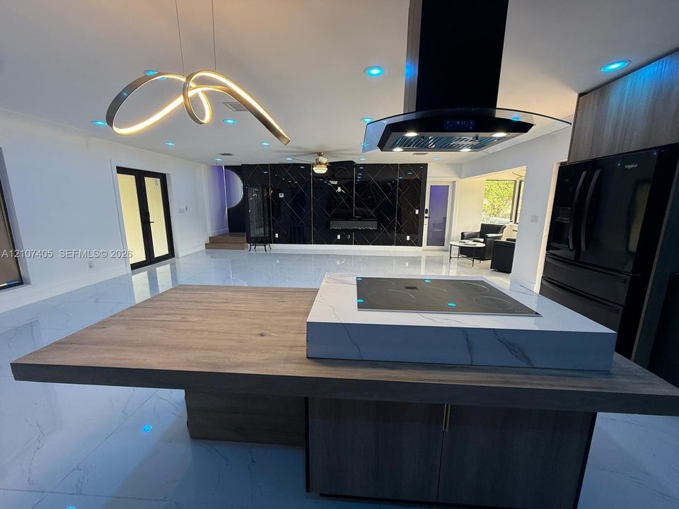 Kitchen island featuring a wood-finish base, stone-surface countertop, and built-in induction cooktop