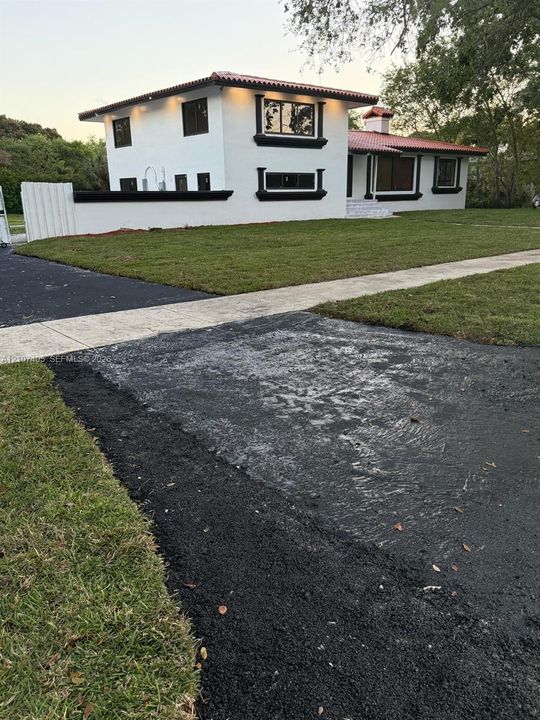Stucco exterior featuring mission-style tile roofing, high-contrast trim detailing, a concrete walkway, and a chimney