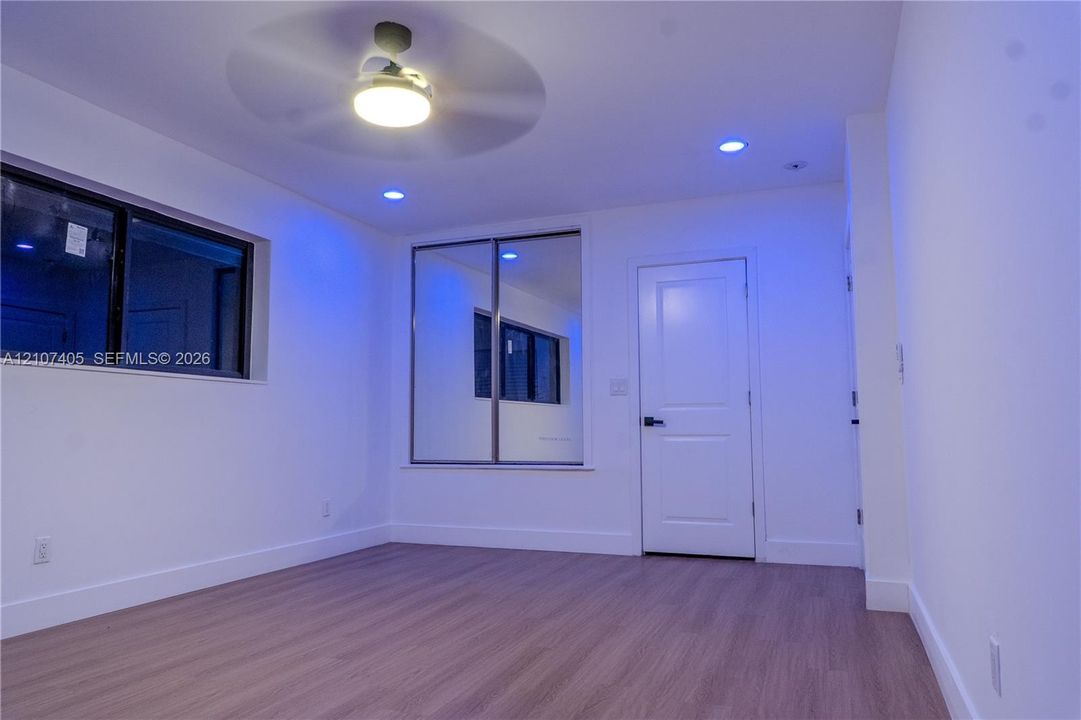 Interior space featuring wood-finish flooring, two-panel interior doors with matte black hardware, and a ceiling-mounted light fixture