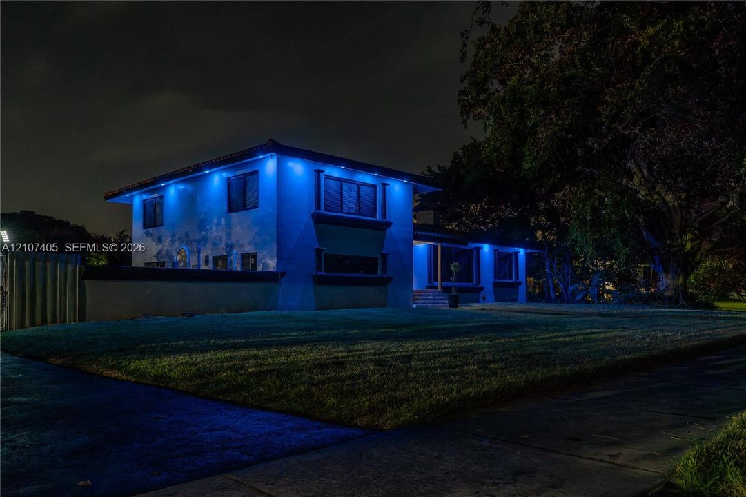 Two-story exterior featuring a flat roofline, stucco siding, multi-pane windows with decorative trim, and a concrete perimeter wall