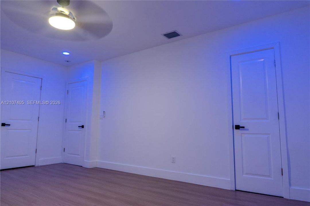 Walk-in shower enclosure featuring large-format tile wall surrounds, a recessed wall niche, a frameless glass door, and a square overhead rainfall showerhead