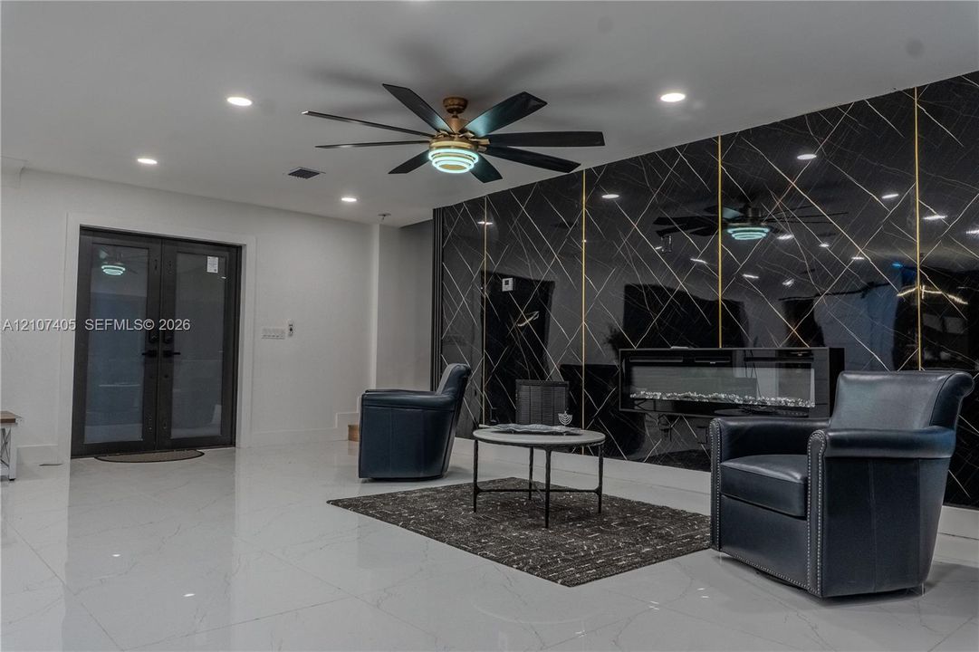 Interior room featuring wood-finish flooring, recessed lighting, a ceiling fan with integrated light fixture, and a single-panel interior door with matte black hardware