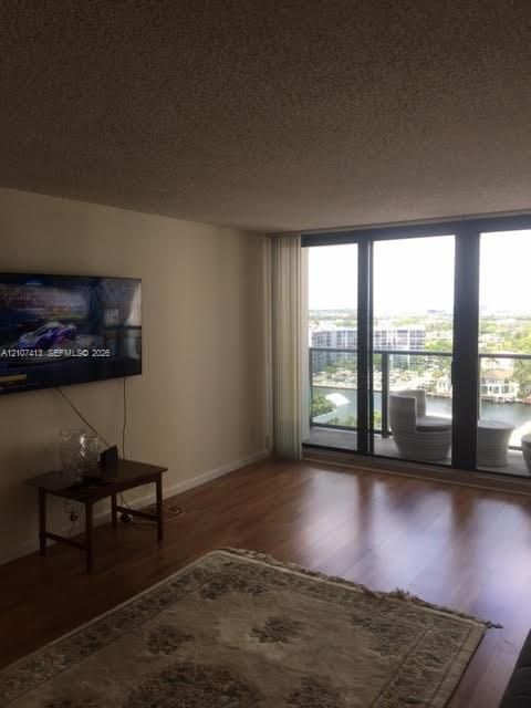 Living area featuring wood-finish flooring and floor-to-ceiling sliding glass doors providing access to a private balcony