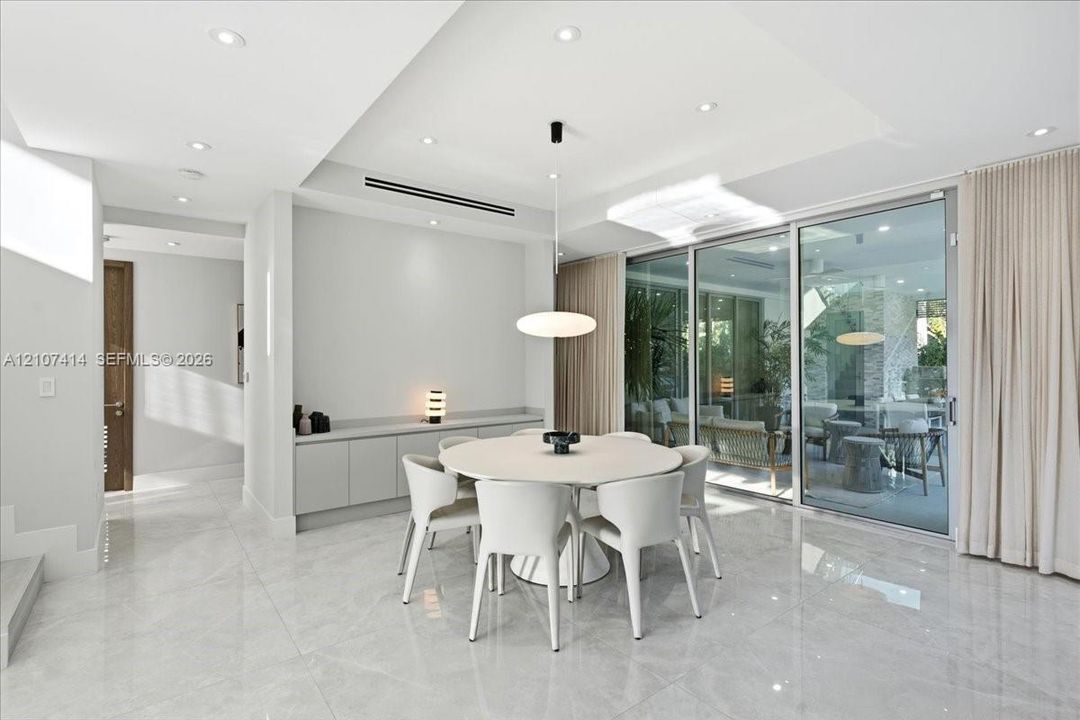 Polished stone-finish flooring, built-in wall cabinetry, recessed ceiling lighting, a modern pendant light fixture, and floor-to-ceiling sliding glass doors