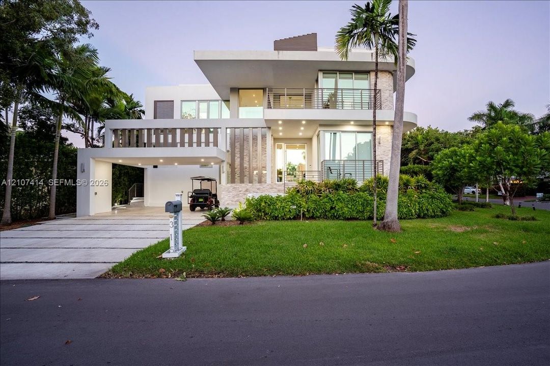 Contemporary architectural exterior featuring multi-level balconies, stone facade accents, expansive floor-to-ceiling windows, and a covered porte-cochere