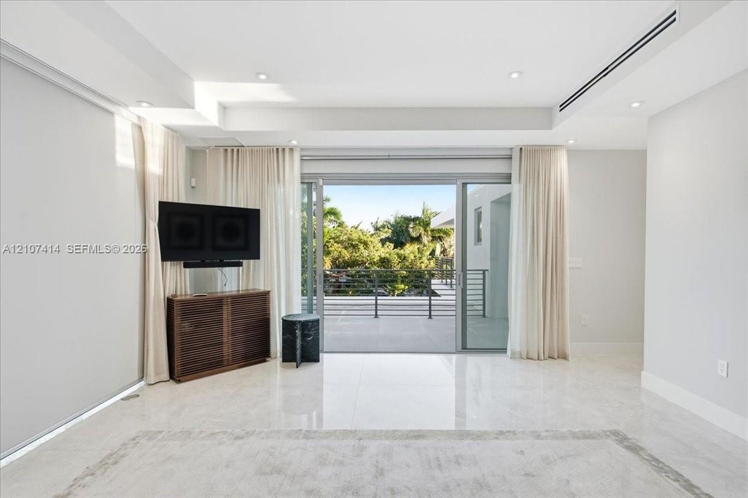 Interior space featuring polished stone flooring, recessed ceiling lighting, a linear HVAC diffuser, and expansive multi-panel sliding glass doors opening to a covered balcony