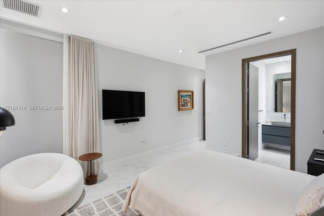 Neutral-toned interior featuring recessed lighting, smooth wall finishes, stone-style flooring, and floor-to-ceiling drapery
