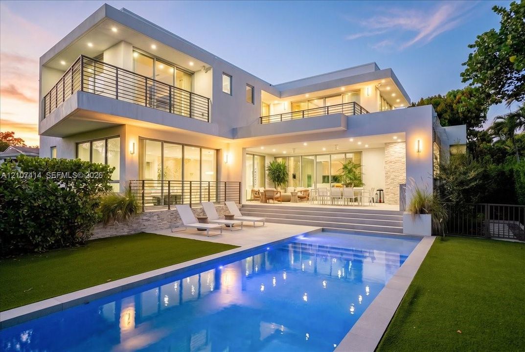 Contemporary exterior featuring tiered balconies with metal railings, expansive floor-to-ceiling glass sliding doors, recessed lighting, stone veneer accents, and an integrated swimming pool with a stone-paved deck