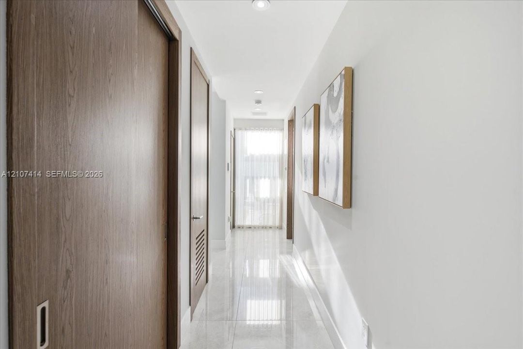 Hallway featuring polished tile flooring, recessed ceiling lighting, and wood-finish doors with integrated hardware
