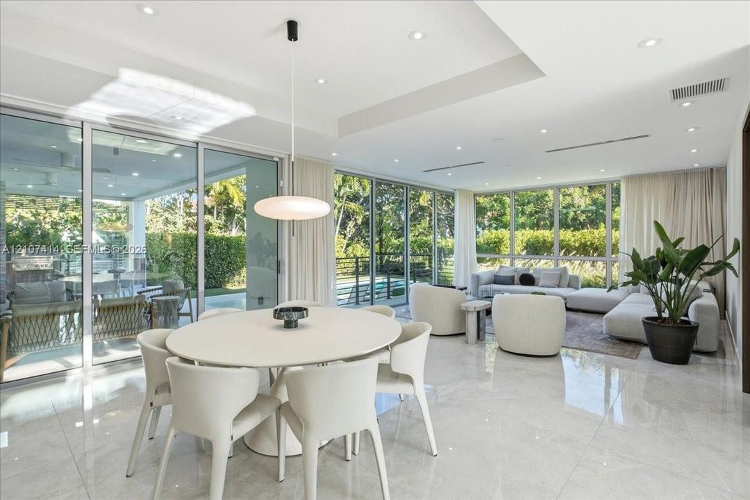 Open-concept interior featuring large-format tile flooring, recessed ceiling lighting, a tray ceiling detail, and floor-to-ceiling glass sliding doors