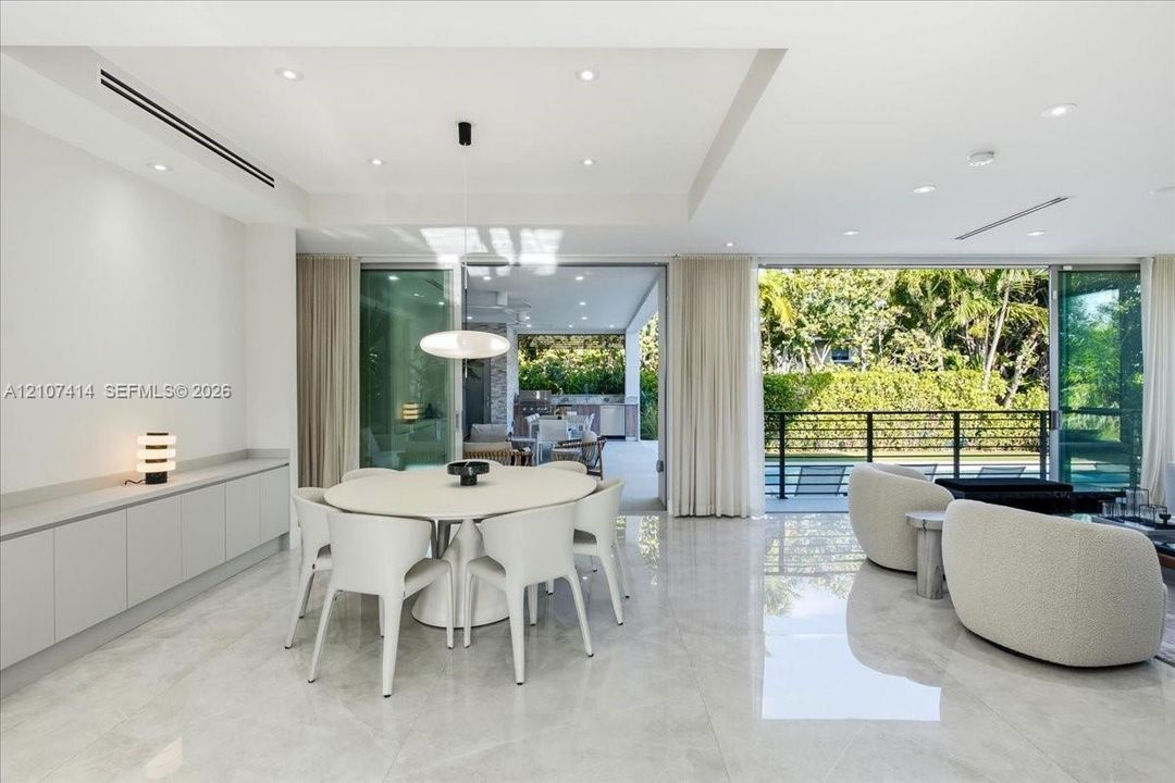 Large-format polished tile flooring, recessed ceiling lighting, built-in floor-to-ceiling cabinetry, and expansive multi-panel sliding glass doors