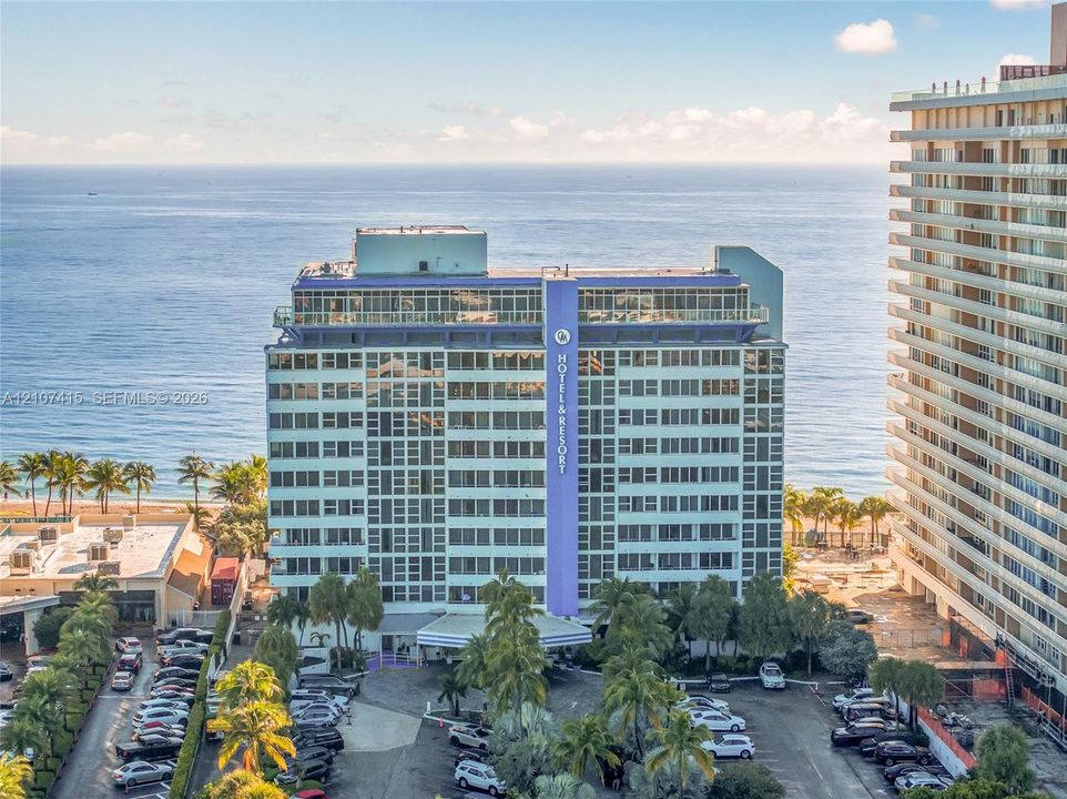 Multi-story residential building featuring a glass-paneled facade, private balconies, and direct oceanfront positioning