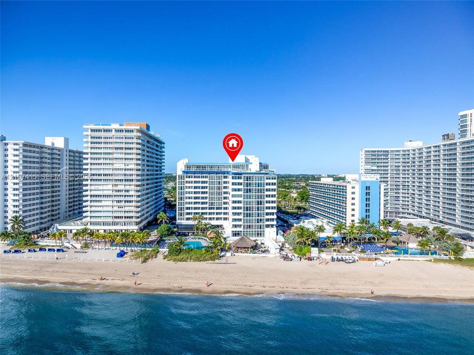 High-rise beachfront condominium building featuring direct ocean access, coastal exterior architecture, and multiple levels of glass-paneled balconies