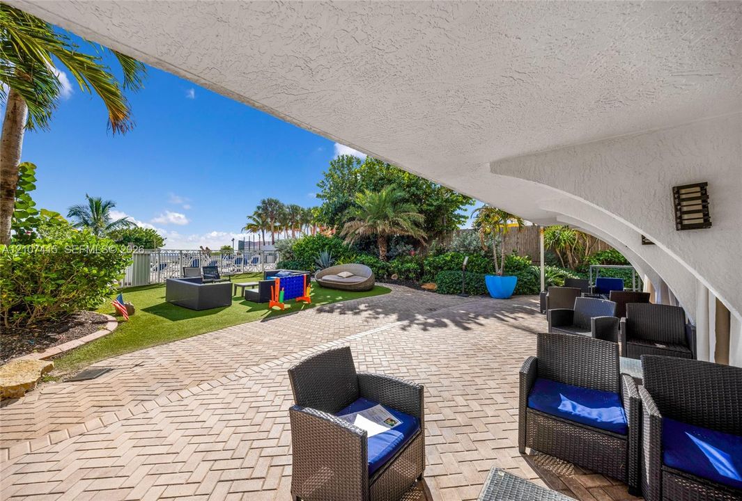 Covered concrete patio with herringbone-patterned pavers, textured stucco ceiling, and wall-mounted exterior lighting