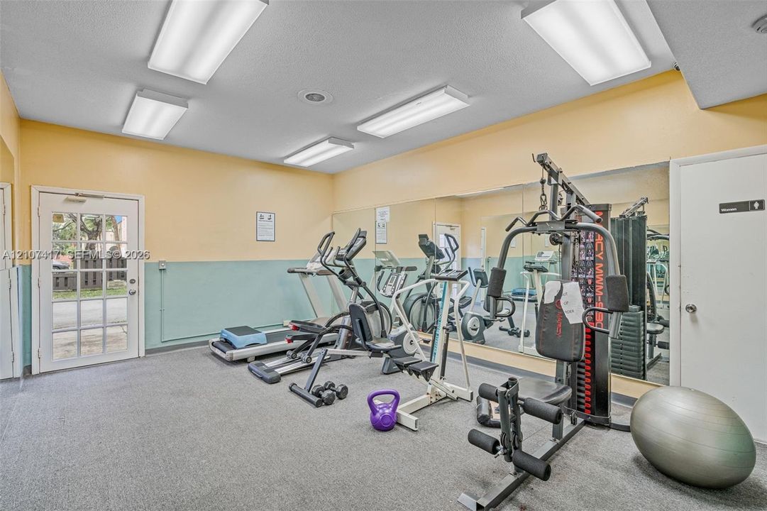 Fitness space featuring full-wall mirrors, recessed lighting, and a glass-panel exterior door