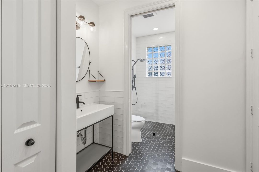 Bathroom featuring a console-style vanity with a rectangular sink, matte black plumbing fixtures, white subway tile wall treatments, and hexagonal floor tiling