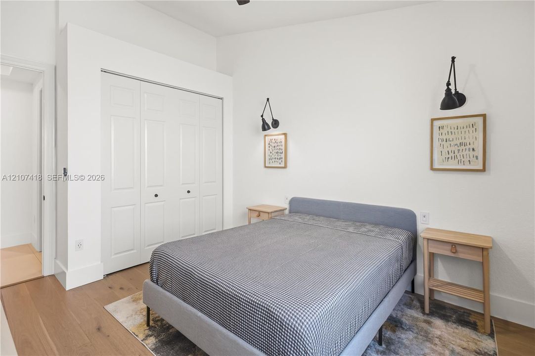 Room featuring wood-finish flooring, white bi-fold closet doors, and dual black wall-mounted swing-arm sconces