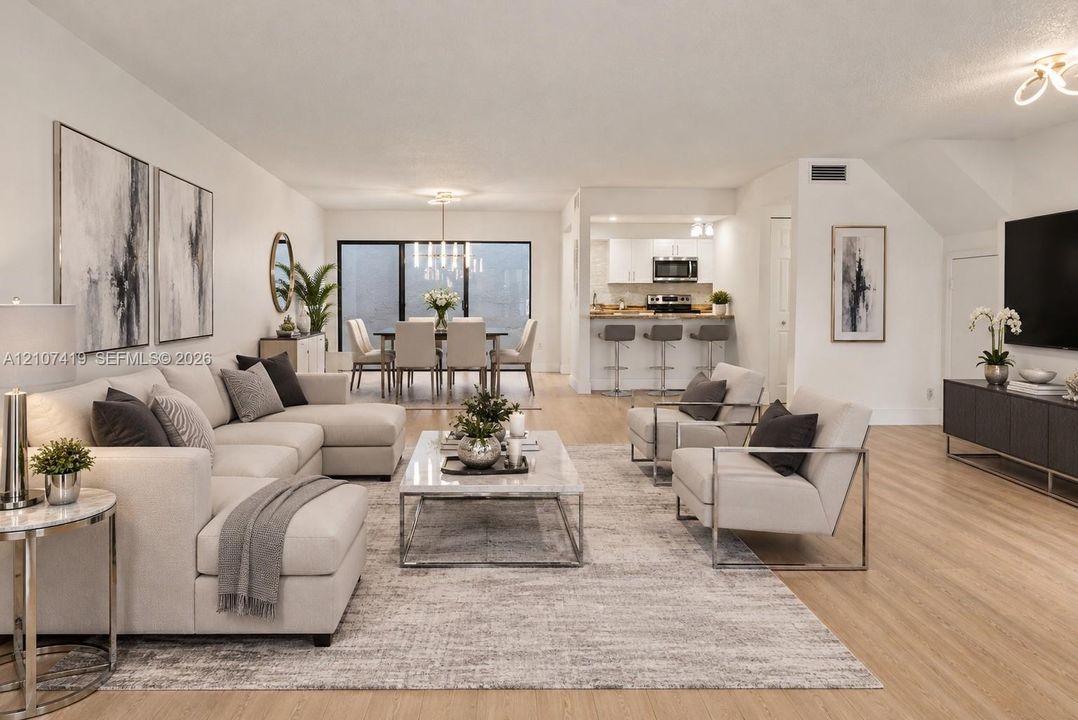 Open concept living area featuring wood-finish flooring, kitchen breakfast bar, and multiple contemporary light fixtures