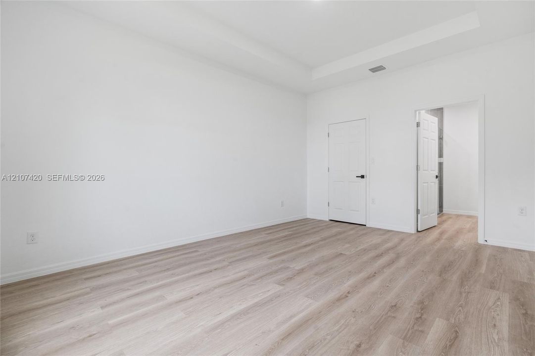 Interior space featuring a tray ceiling, neutral wall tones, and wood-finish flooring
