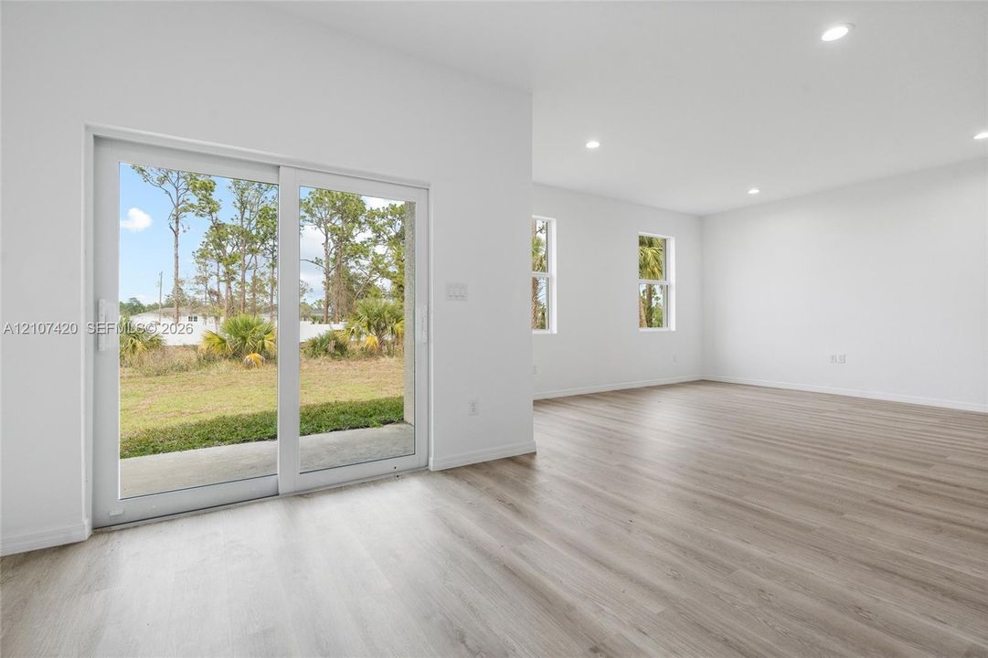 Interior space featuring wood-finish flooring, recessed lighting, and large sliding glass doors leading to an exterior concrete patio