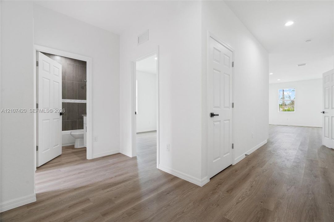 Interior space featuring wood-finish flooring, recessed lighting, and multi-panel interior doors with matte black hardware