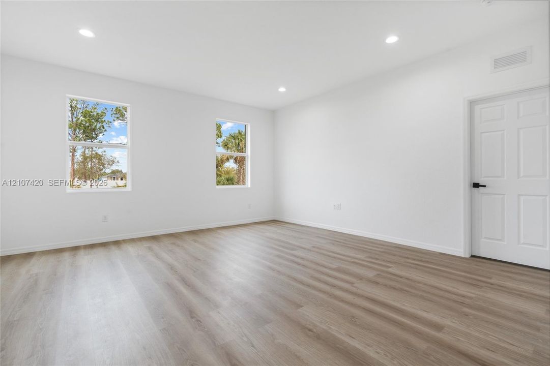 Interior space featuring wood-finish flooring, recessed lighting, dual windows, and a six-panel door with matte black hardware