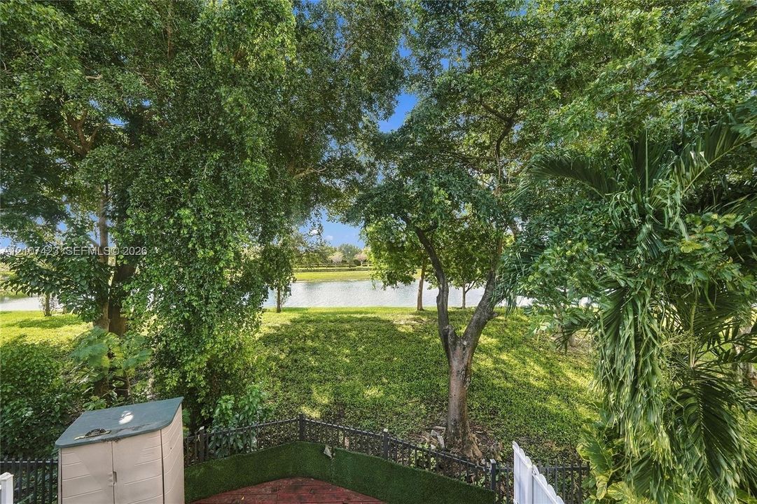 Backyard featuring mature trees, a water feature, ground-level hardscaping, and decorative perimeter fencing