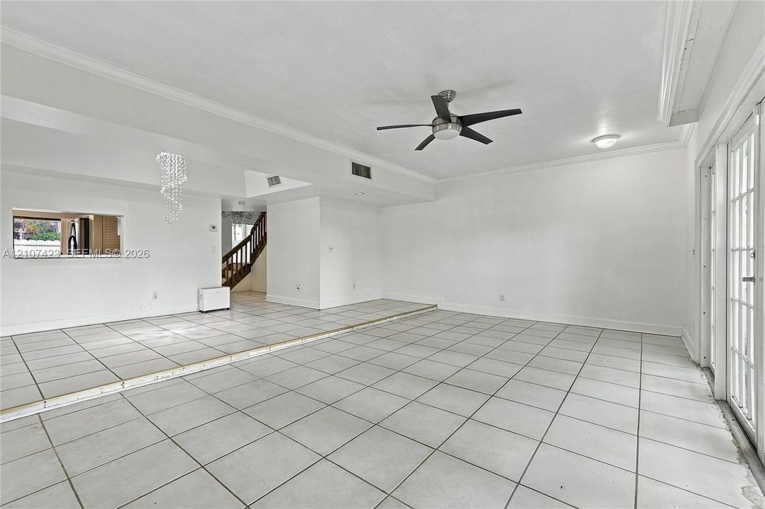 Sunken living area featuring large-format tile flooring, a tiered floor plan, a ceiling fan, and multi-pane glass doors