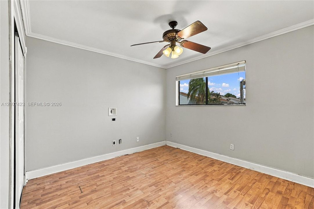 Wood-finish flooring, neutral wall tones, multi-light ceiling fan, and horizontal window blinds