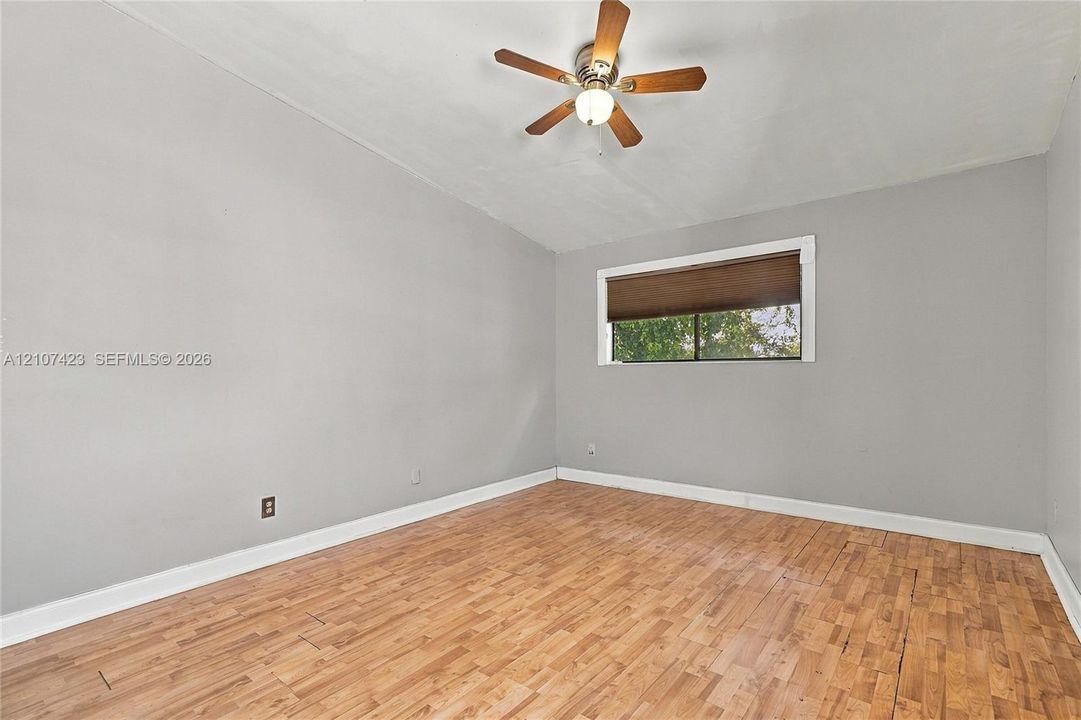 Room featuring wood-finish flooring, neutral wall paint, and a ceiling-mounted fan with integrated light fixture