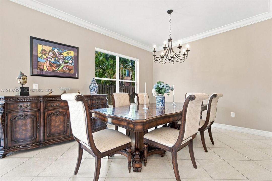 Dining area featuring neutral wall paint, tile flooring, crown molding, and an eight-light chandelier