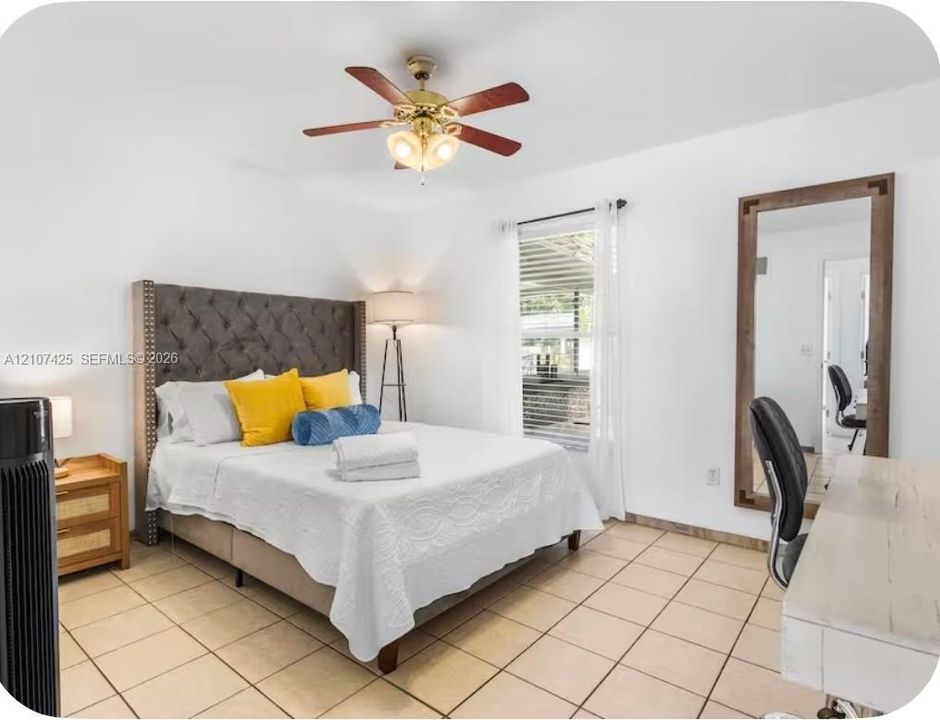 Neutral-toned ceramic tile flooring, ceiling fan with integrated lighting, and a single-pane window