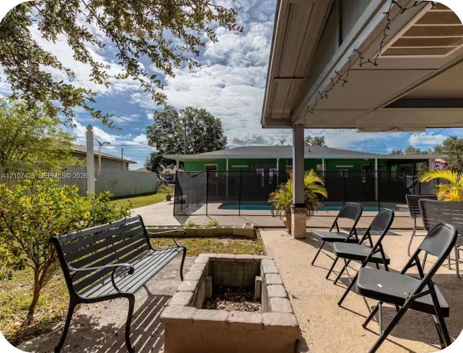 Covered patio featuring a concrete surface, built-in stone fire pit, and enclosed pool area