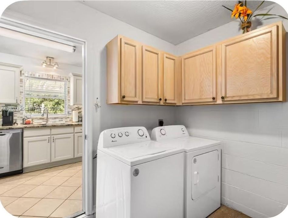 Laundry area featuring light wood-finish upper cabinetry, painted masonry walls, and white appliance hookups