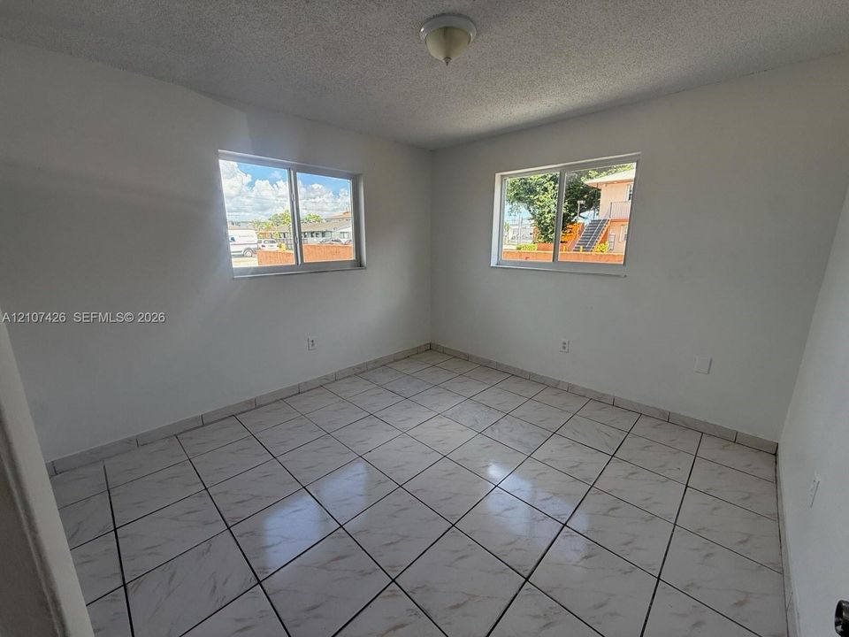Neutral-toned walls paired with large-format tile flooring and dual sliding windows providing natural light