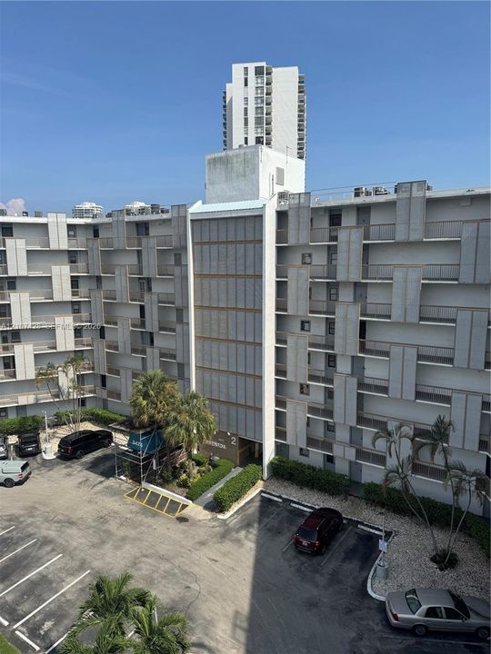 Multi-story residential complex featuring geometric facade detailing, exterior-facing balconies, and dedicated surface parking