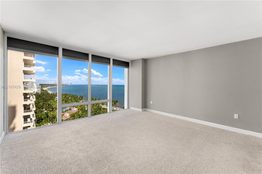 Private covered balcony featuring neutral tile flooring, glass sliding door access, and ocean backdrop