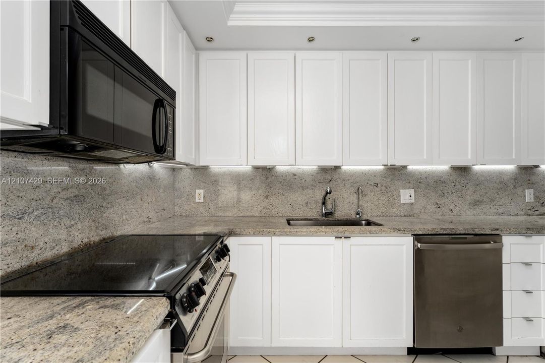 Interior hall featuring white tile flooring, floor-to-ceiling louvered closet doors, and multiple entryways showcasing direct water and shoreline scenery