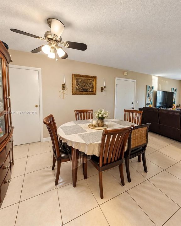 Light-toned tile flooring, neutral wall paint, three-light ceiling fan with integrated glass shades, and dual wall-mounted sconces