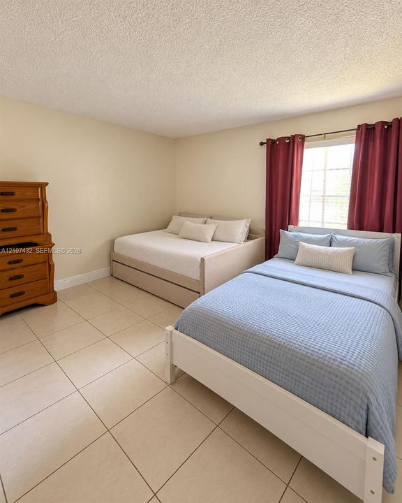 Interior room featuring large-format tile flooring, neutral wall paint, and a window with a grid pattern