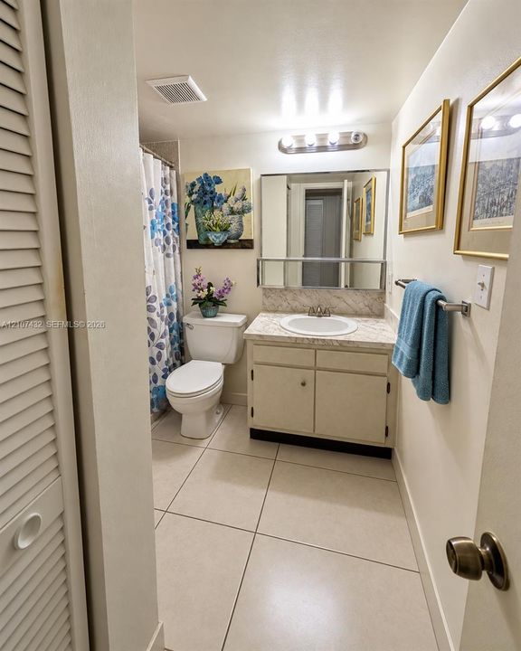 Bathroom featuring large-format tile flooring, vanity with a stone-finish countertop, integrated basin, and a wall-mounted medicine cabinet with a mirror