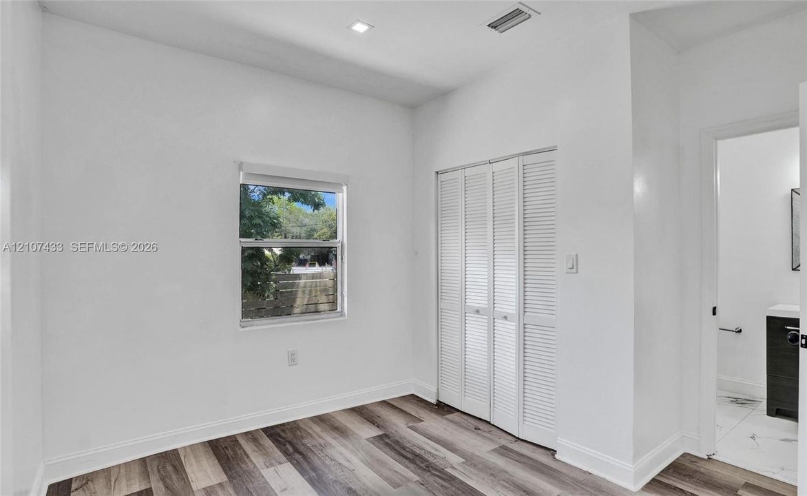 Rear patio featuring concrete paver flooring, a raised wooden deck with staircase, and perimeter wood privacy fencing