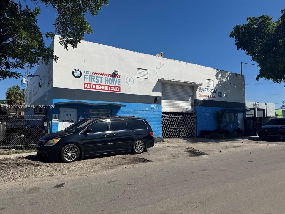 Industrial warehouse building featuring a masonry exterior, high-clearance roll-up door, metal security gate, and paved exterior space
